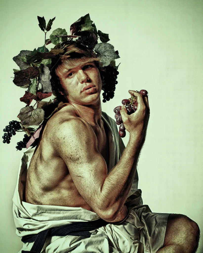 Bare-chested man crowned with grape leaves in dramatic light