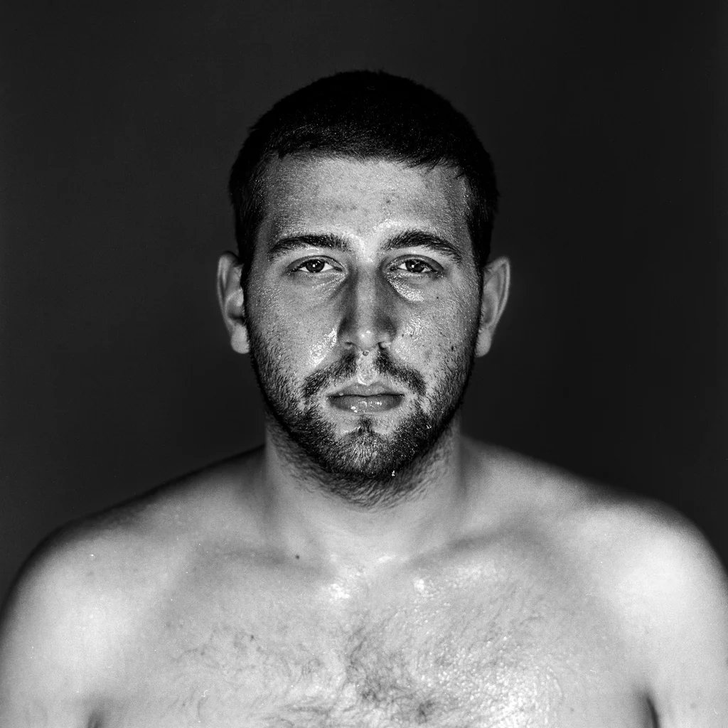 Black-and-white portrait of a shirtless man facing forward