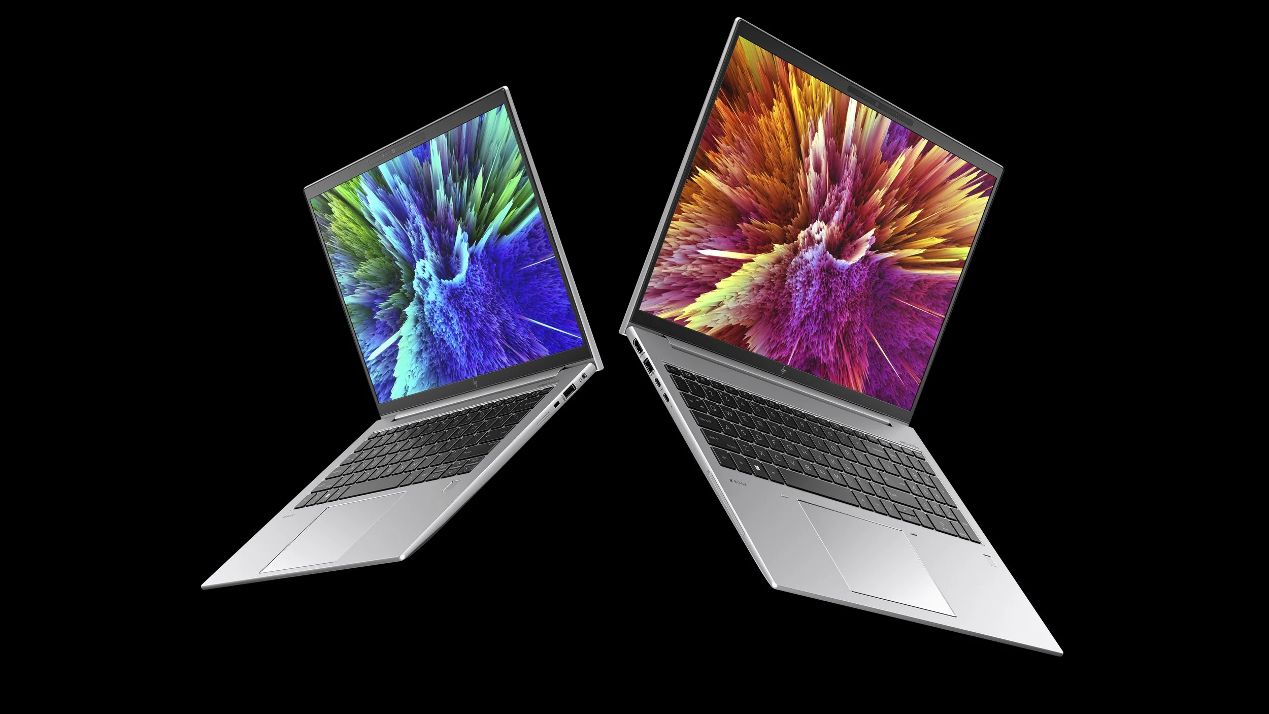 Two open silver laptops angled toward each other on black