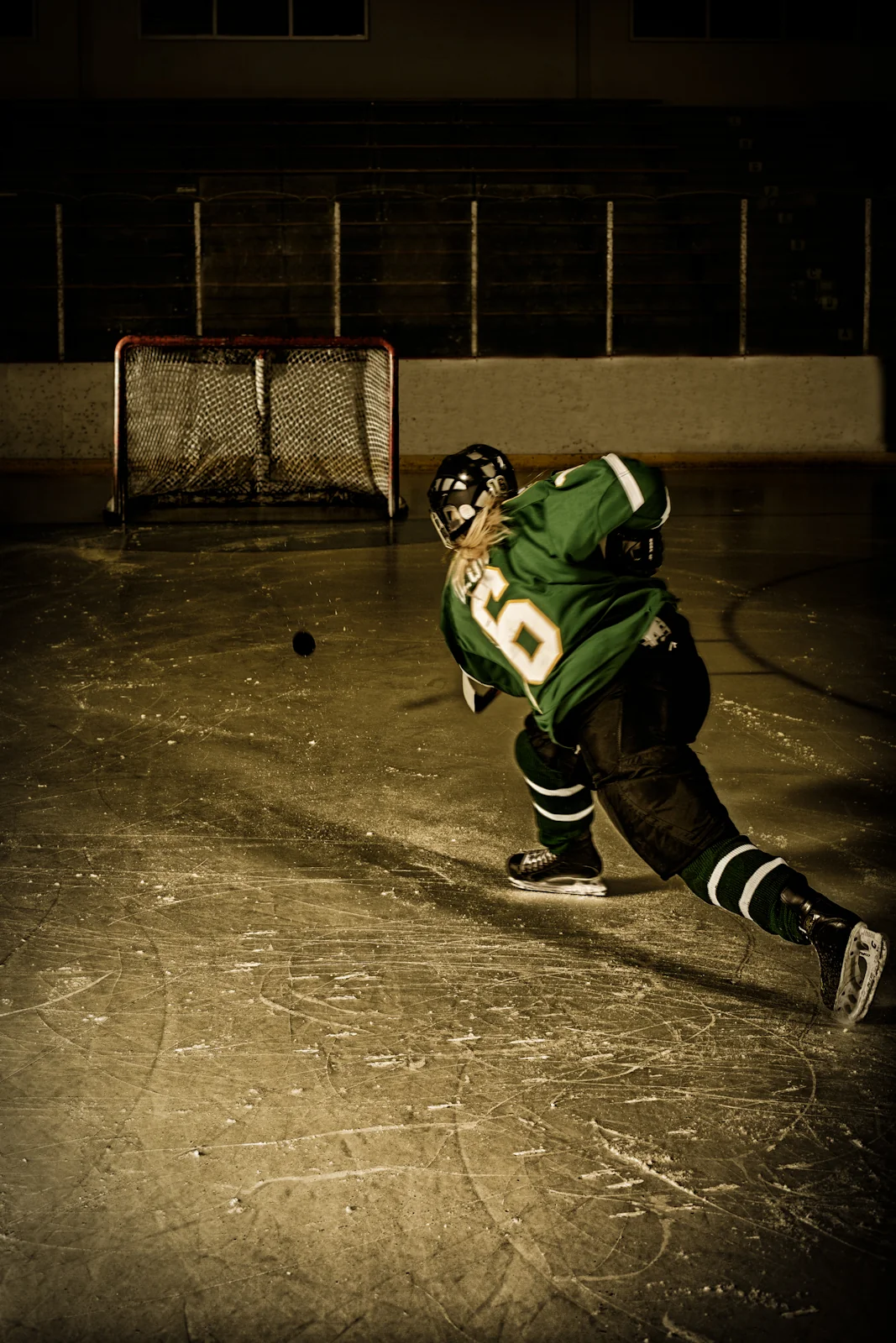 Hockey player leaning over a stick on dark ice