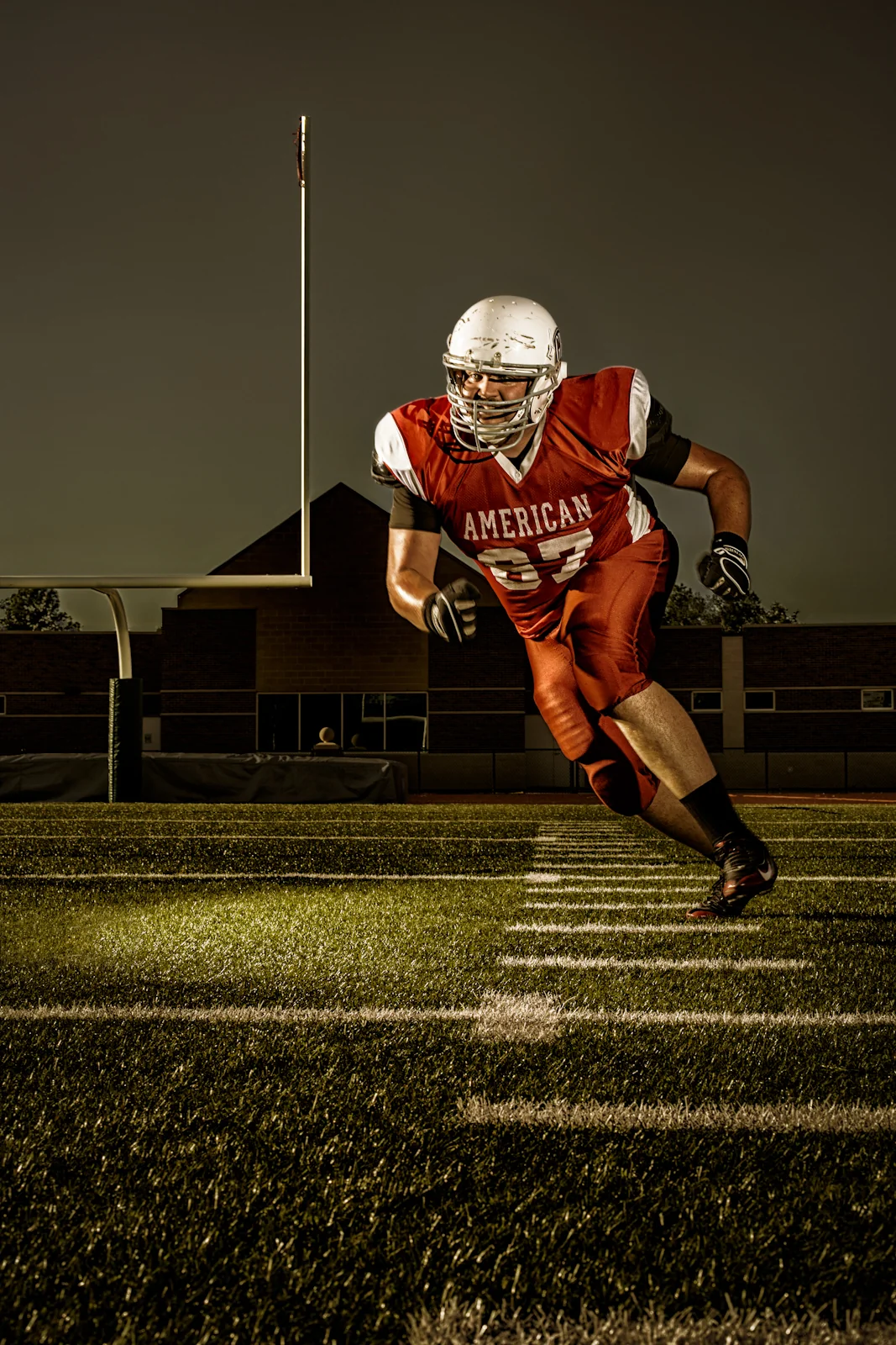 Football player in red running across a lit field